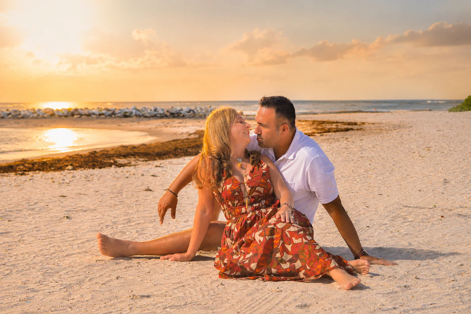 Pareja sentada junto al mar durante el atardecer